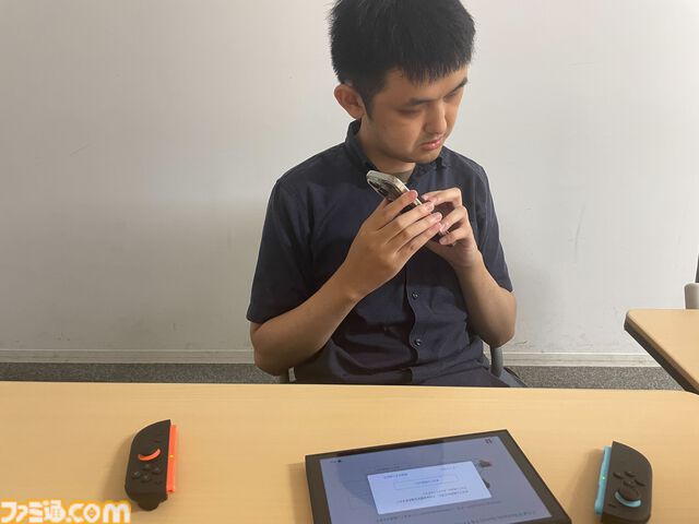 野澤さんがスマホの写真機能でSwitchの画面を写し、視覚障害者支援ソフトSeeing AIで読み上げしているところ